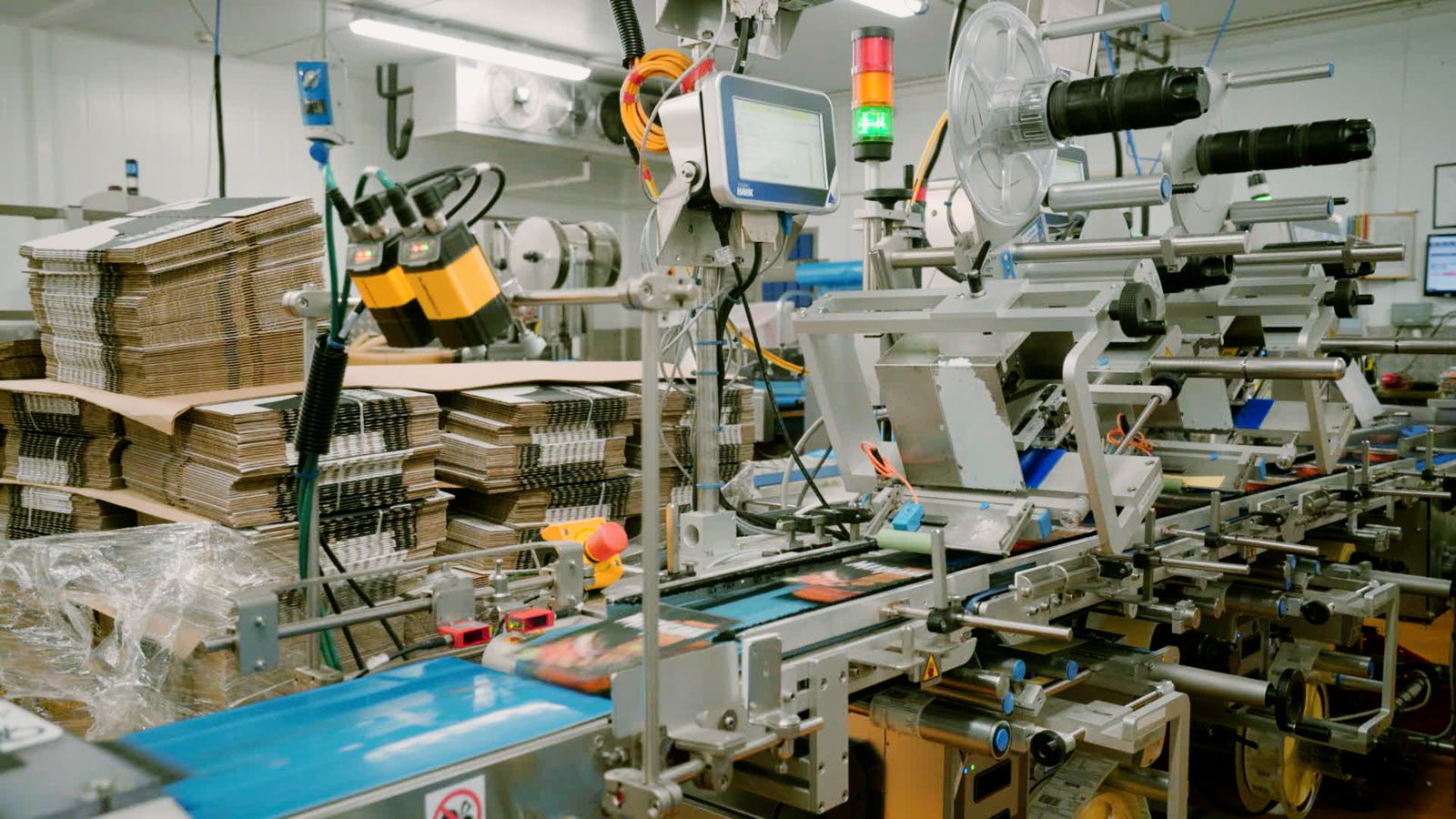 An inline coder and camera inspection station on a food packing line, printing and checking codes on packs as they pass
